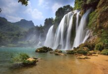 Осень или весна? Лучшие направления для путешествий в сентябре Majestic view of Ban Gioc Waterfall cascading into a serene pool amidst lush greenery in Cao Bang, Vietnam.