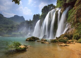 Осень или весна? Лучшие направления для путешествий в сентябре Majestic view of Ban Gioc Waterfall cascading into a serene pool amidst lush greenery in Cao Bang, Vietnam.