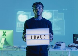 Масштабная реформа Уголовного кодекса Канады вступила в силу Man holding a 'FRAUD' sign in a tech setting, symbolizing cybersecurity threats.
