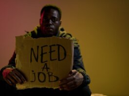 Полиция Лондона просит помощи в расследовании мошенничества в LHSC Man with a cardboard sign seeking employment, highlighting unemployment and social issues.