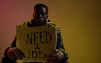 Man with a cardboard sign seeking employment, highlighting unemployment and social issues.