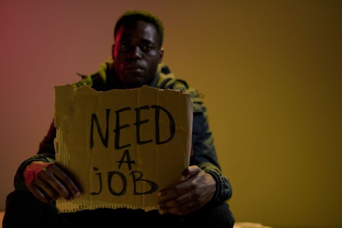 Man with a cardboard sign seeking employment, highlighting unemployment and social issues. Man with a cardboard sign seeking employment, highlighting unemployment and social issues.