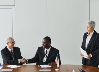 Канада и Франция подписали соглашение об обмене секретной информацией Multinational business meeting with agreement signing, featuring diverse professionals and flags.