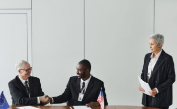 Канада и Франция подписали соглашение об обмене секретной информацией Multinational business meeting with agreement signing, featuring diverse professionals and flags.