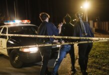 В Лондоне при задержании угнанного авто изъяли обрезы и наркотики Nighttime arrest scene with police officers and patrol car behind caution tape.