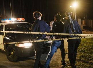 В Лондоне при задержании угнанного авто изъяли обрезы и наркотики Nighttime arrest scene with police officers and patrol car behind caution tape.