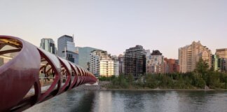 Peace Bridge spans the Bow River with Calgary's skyline in the background during a serene evening.
