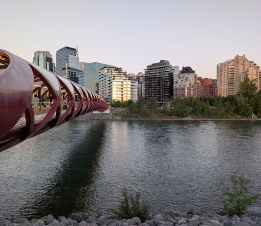 Peace Bridge spans the Bow River with Calgary's skyline in the background during a serene evening.