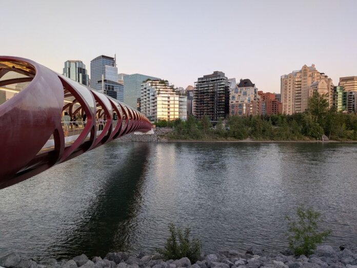 Peace Bridge spans the Bow River with Calgary's skyline in the background during a serene evening. Peace Bridge spans the Bow River with Calgary's skyline in the background during a serene evening.