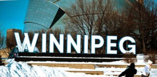 People ice skating in front of the iconic Winnipeg sign on a sunny winter day.