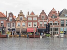 Picturesque European street featuring traditional Dutch gabled buildings and open air cafes.