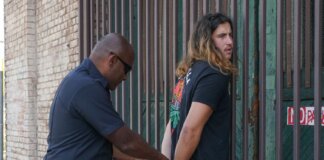 Police officer handcuffing a suspect during an arrest against an urban backdrop.