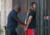 Police officer handcuffing a suspect during an arrest against an urban backdrop.