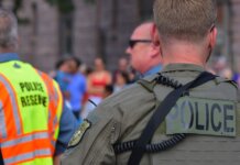 Лондон (Онтарио) отмечает 30-летие партнёрства полиции с центром ДТП Police officers maintaining security at a public event with a crowd in the background.