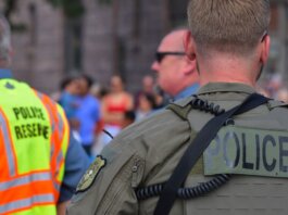 Police officers maintaining security at a public event with a crowd in the background.