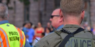 Police officers maintaining security at a public event with a crowd in the background.