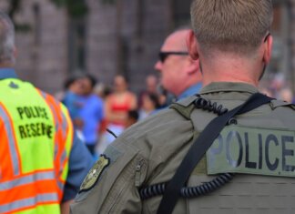 Лондон (Онтарио) отмечает 30-летие партнёрства полиции с центром ДТП Police officers maintaining security at a public event with a crowd in the background.