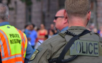 Police officers maintaining security at a public event with a crowd in the background.