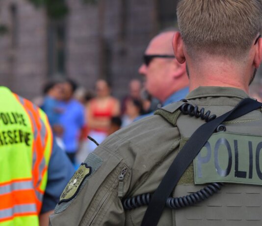 Police officers maintaining security at a public event with a crowd in the background.