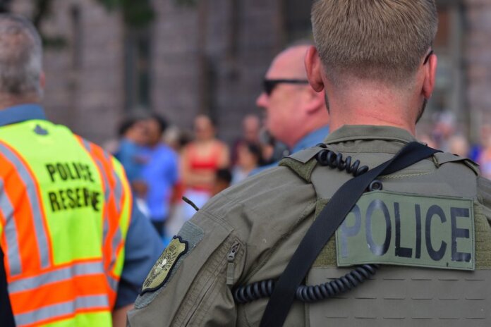 Police officers maintaining security at a public event with a crowd in the background.