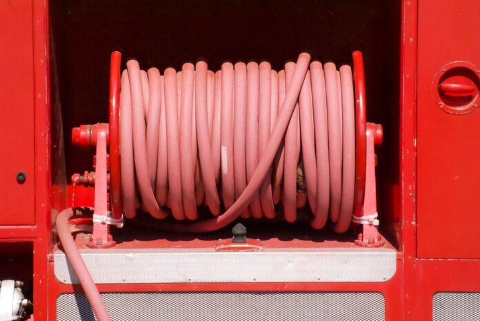 Red fire hose coiled neatly on a fire truck in Bow of Fife, Scotland.