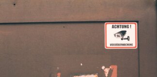 Rusty industrial door with a German surveillance warning sign