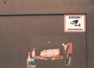 Rusty industrial door with a German surveillance warning sign