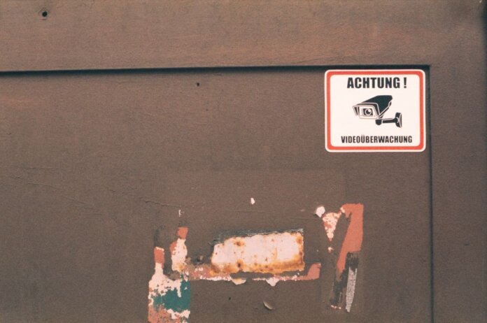 Rusty industrial door with a German surveillance warning sign