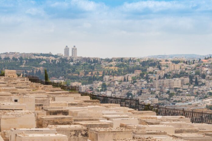 Scenic view of Jerusalem, Israel, featuring a historic cemetery and urban landscape under a blue sky.