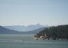 Serene landscape of a lighthouse by the sea with mountains in the background.