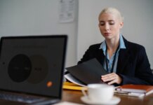 Serious young woman in formal clothes sitting at table and working with documents in office