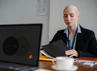 Serious young woman in formal clothes sitting at table and working with documents in office