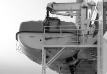 Side view of a lifeboat secured on a ship deck in black and white.