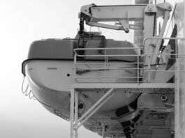 Side view of a lifeboat secured on a ship deck in black and white.