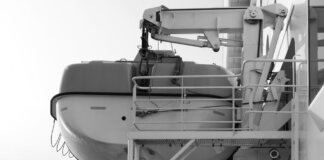 Side view of a lifeboat secured on a ship deck in black and white.