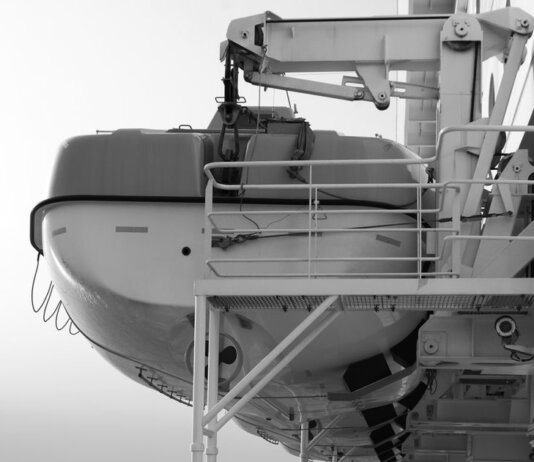 Side view of a lifeboat secured on a ship deck in black and white.