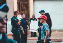 Street protest in Wheeling, WV highlighting immigration issues with signs and police presence.
