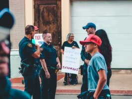 Street protest in Wheeling, WV highlighting immigration issues with signs and police presence.