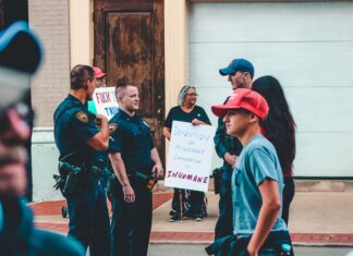 Street protest in Wheeling, WV highlighting immigration issues with signs and police presence.
