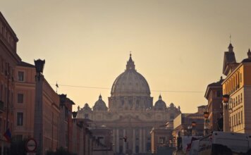 Street view of Saint Peter's Basilica in Vatican City during dusk, capturing the iconic architecture and Roman skyline.