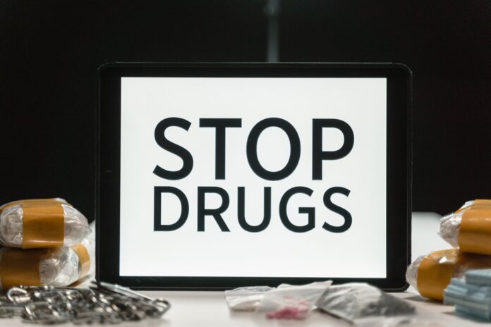 Tablet screen displaying anti-drug message surrounded by packaged substances, promoting awareness. Tablet screen displaying anti-drug message surrounded by packaged substances, promoting awareness.