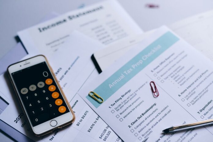Tax preparation setup with documents, smartphone calculator, and checklist. Tax preparation setup with documents, smartphone calculator, and checklist.