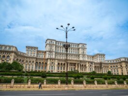 The grand Palace of the Parliament under a blue sky in Bucharest, Romania, showcasing neoclassical architecture.
