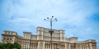 The grand Palace of the Parliament under a blue sky in Bucharest, Romania, showcasing neoclassical architecture.