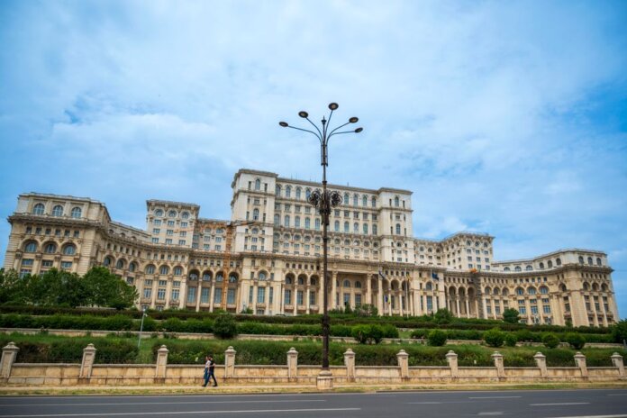 The grand Palace of the Parliament under a blue sky in Bucharest, Romania, showcasing neoclassical architecture.