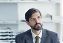 Thoughtful businessman in suit and tie in modern office environment.