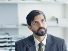 Thoughtful businessman in suit and tie in modern office environment.