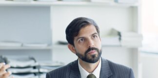 Thoughtful businessman in suit and tie in modern office environment.