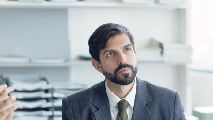 Thoughtful businessman in suit and tie in modern office environment.
