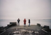 Трое обвиняемых по делу о похищении и ограблении в Калгари Three individuals are standing on a pier overlooking a frozen lake on a cloudy winter day.